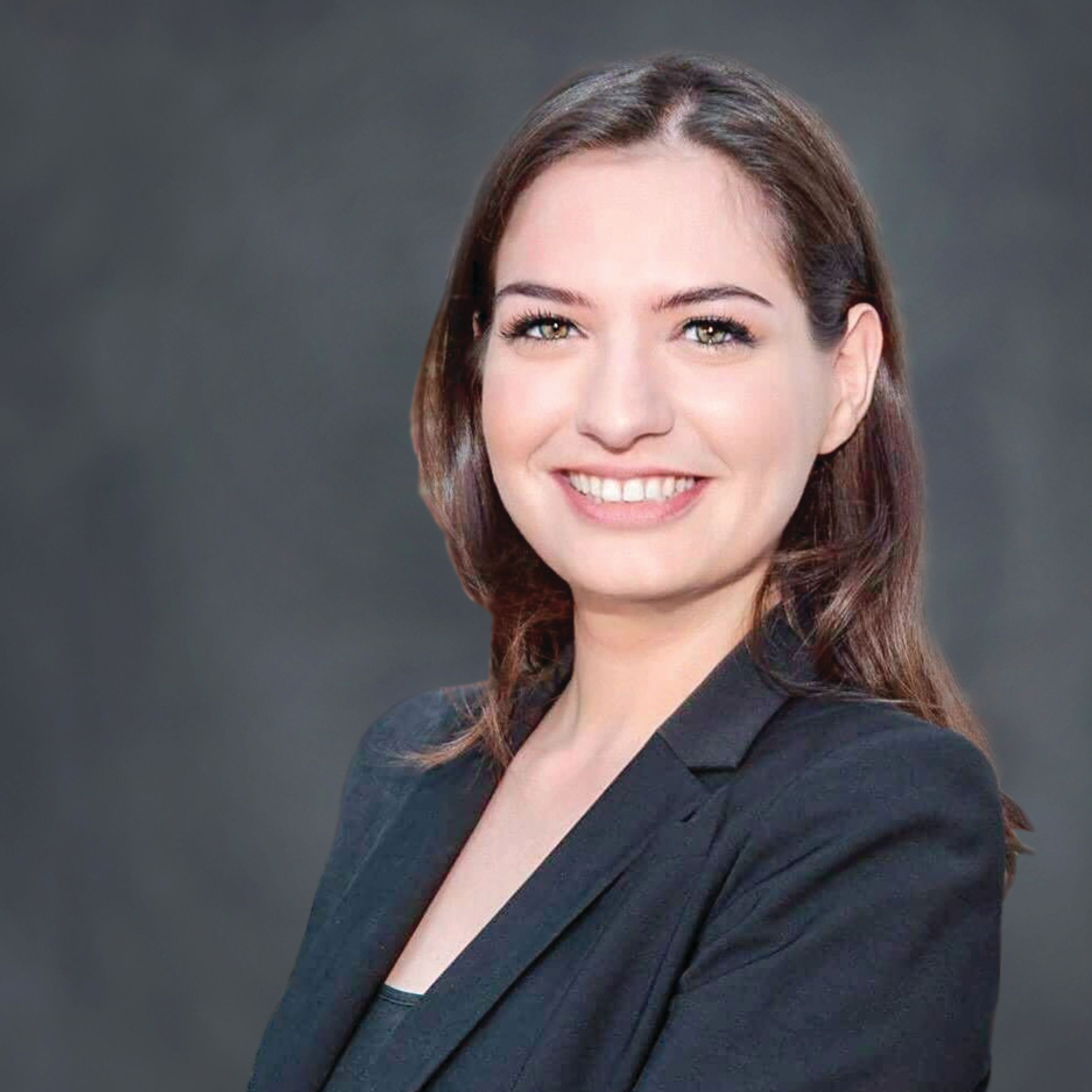 Headshot of Övül Sezer smiling in a black blazer.