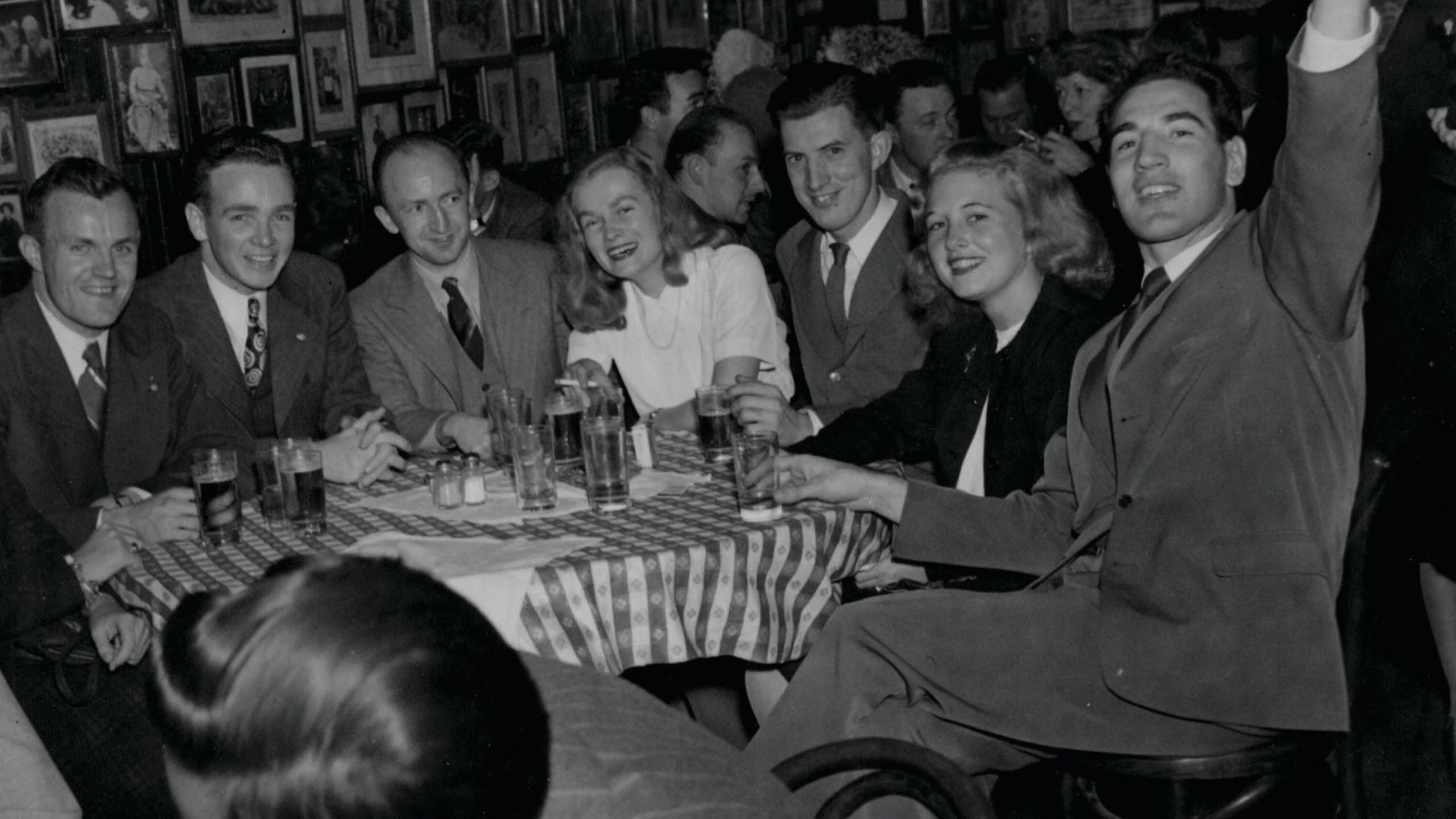 Black and white photo of students sitting at a table with a checkered table cloth.
