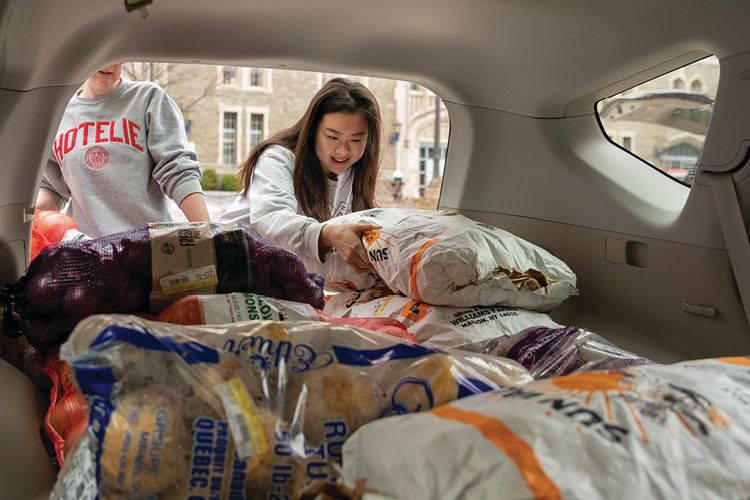 Two students reach into the trunk of a car to grab food.