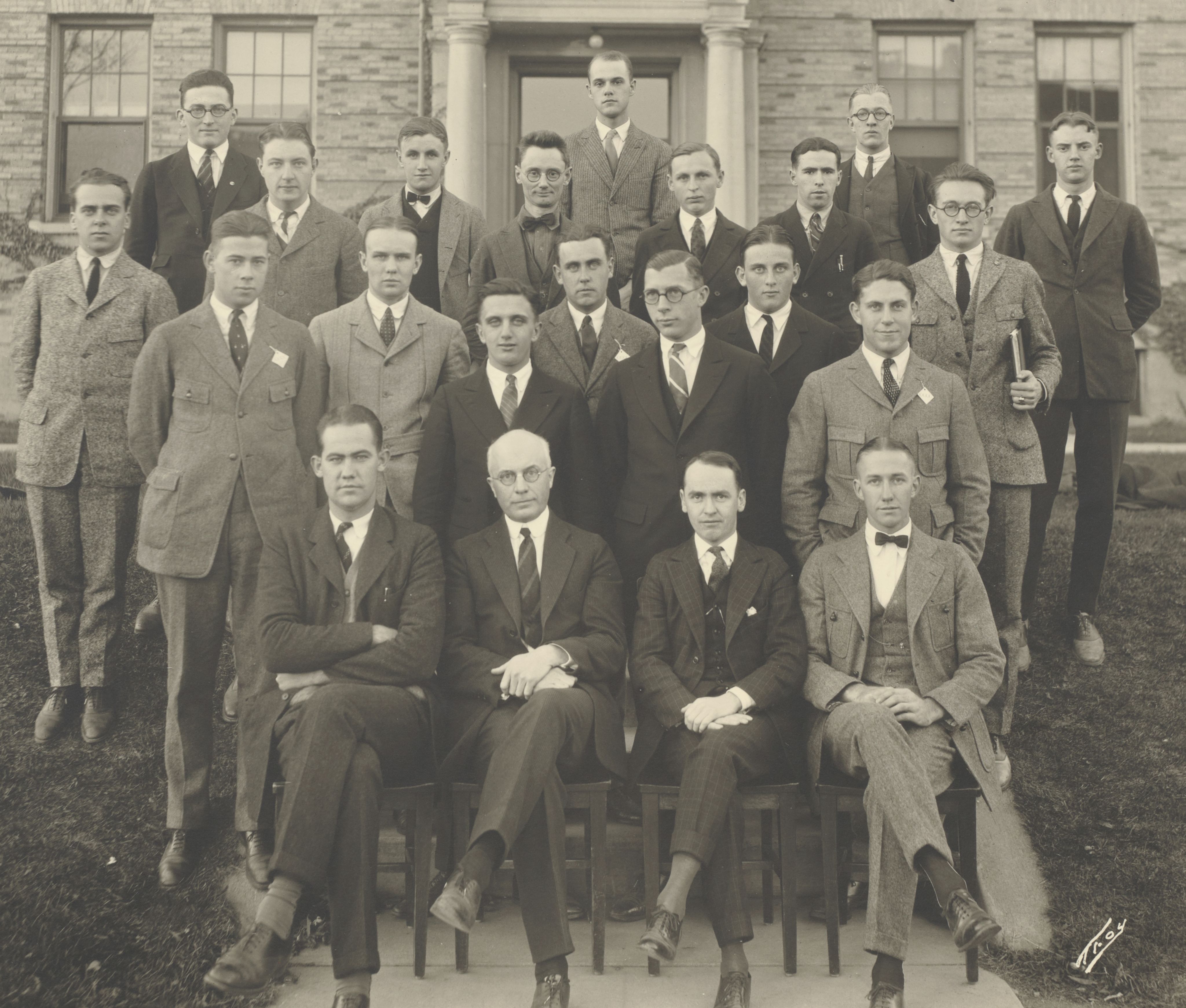 Black and white photo of men in business attire outside of a building